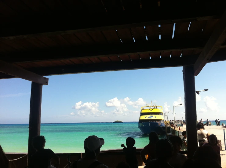 a large boat is docked near people on the shore