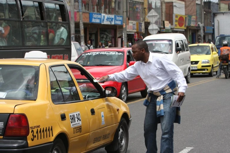 man walking and pointing at taxi cab in city