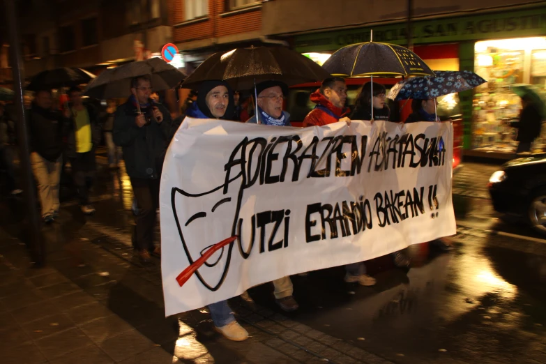 protesters with umbrellas hold a sign that reads'ermendra open'in front of a group of people