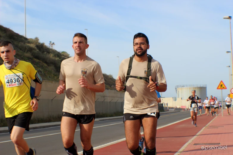 three men running on the road with yellow shirts