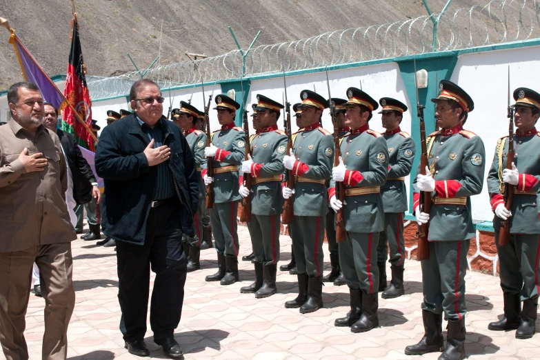 a man talks to some men in uniform