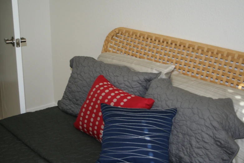 a bed with grey and red pillows and a headboard