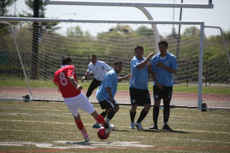 some guys on a field playing soccer and one is going after the ball