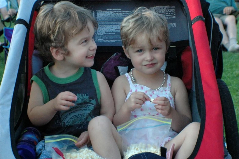 two children are sitting together in the back of a car seat