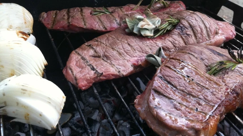 steak and onions cooking on a bbq grill