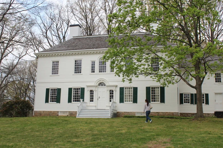 a white house with green shutters stands on grass