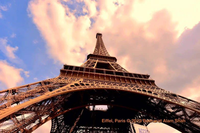 the view of the eiffel tower from below with clouds overhead