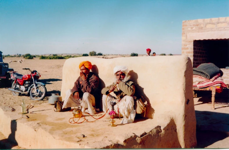 two people sitting on a stone structure with bicycles in the background