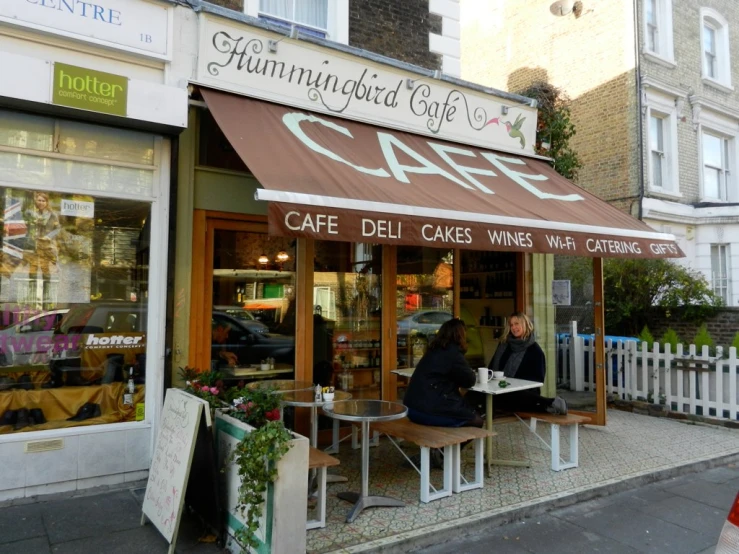 people are eating in front of a cafe on the street