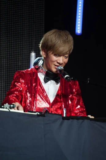 boy in red and black suit on stage with microphone