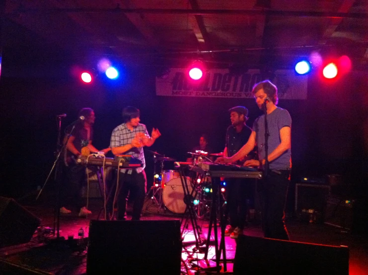 three people with electronic devices playing at a music concert