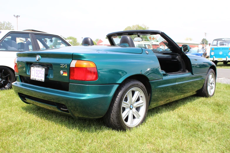 a bmw convertible parked on top of a grass covered field