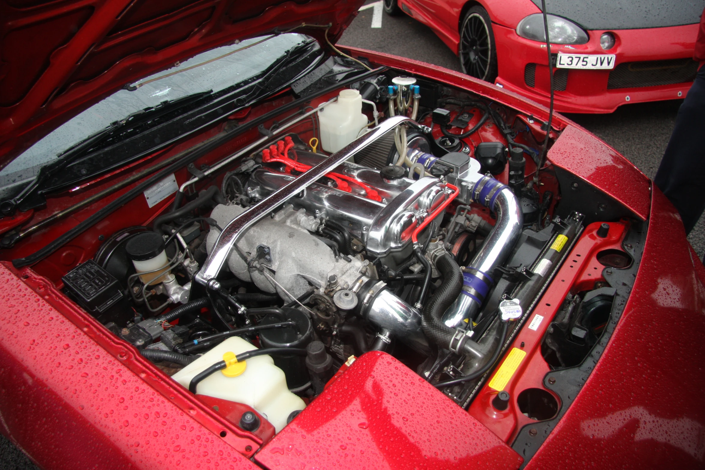 the engine compartment of a sports car parked in front of other vehicles