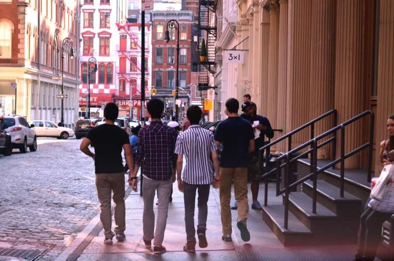 three guys stand on the sidewalk of a downtown street