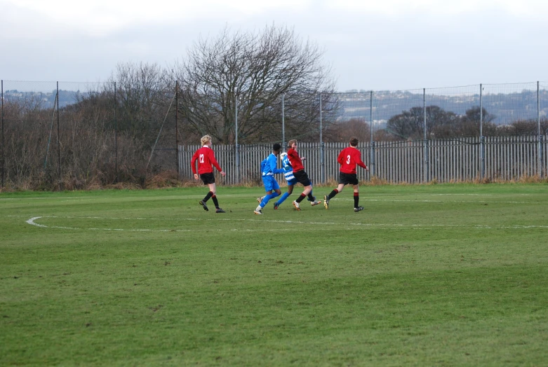 some soccer players running after the ball in a field