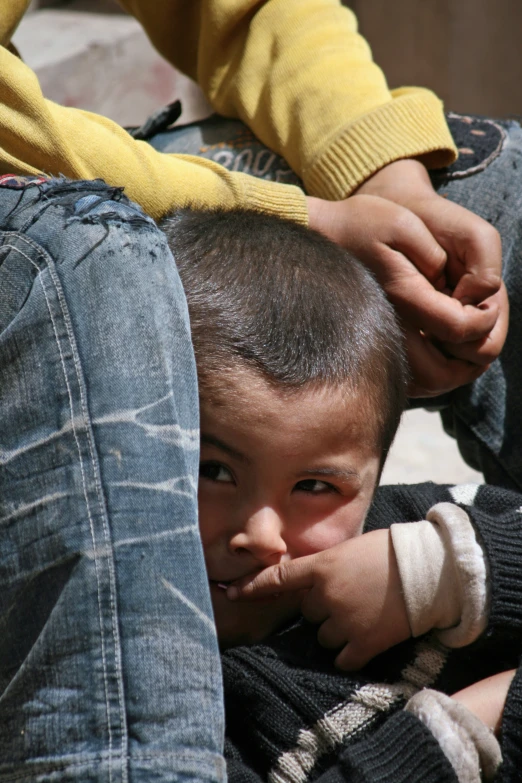 a young child covering his face while sitting next to an adult