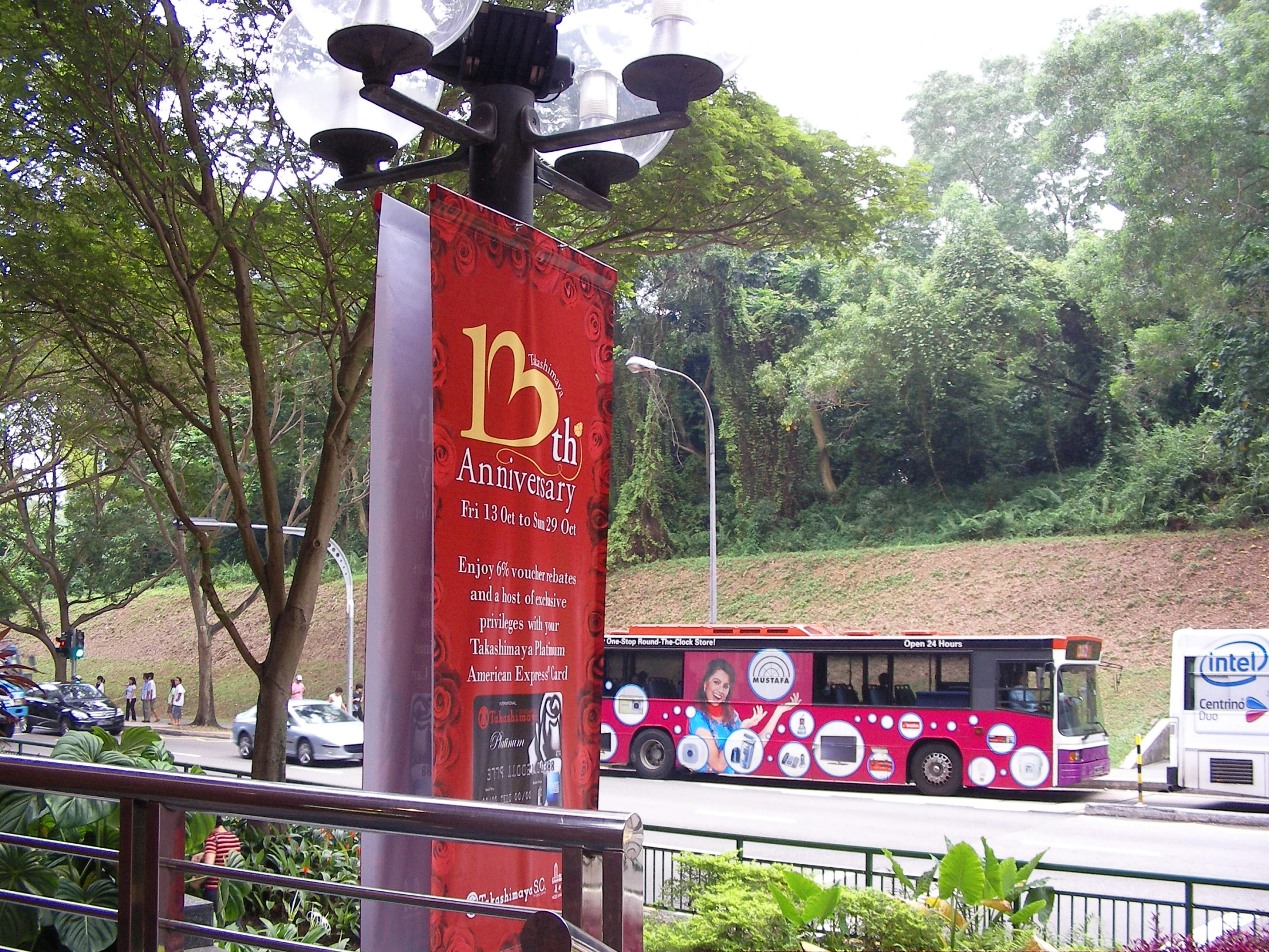 a red bus is next to a tree and lamp post