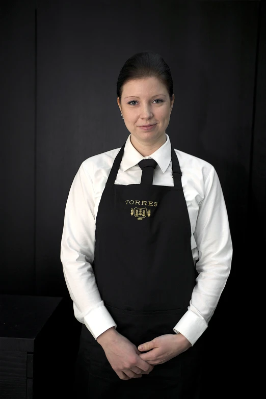 a beautiful young lady wearing a black apron posing for the camera