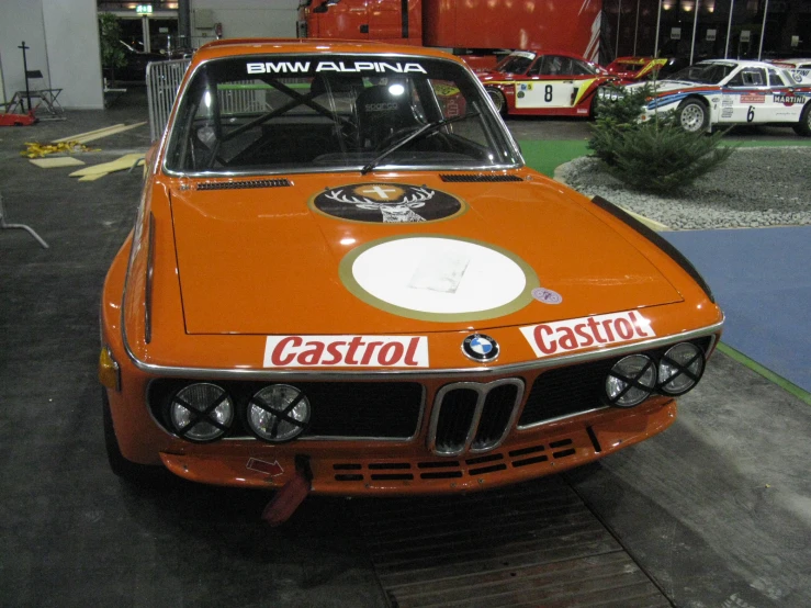 an old orange bmw racing car is parked on the tarmac