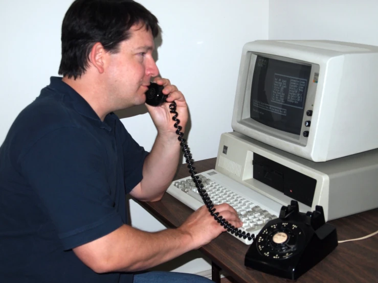 a man that is talking on the telephone and working on a computer
