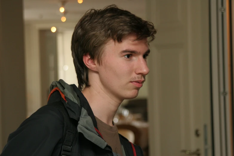 a boy with frecks and backpack standing in a room