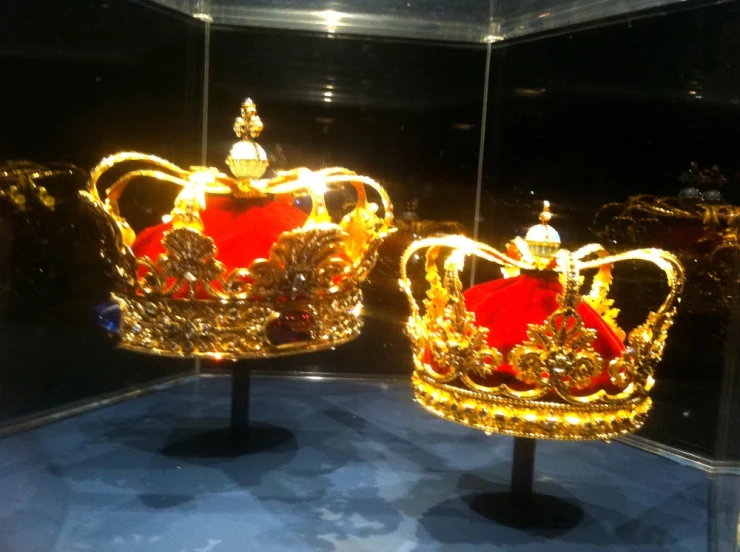 two gold crowns sitting on stands together