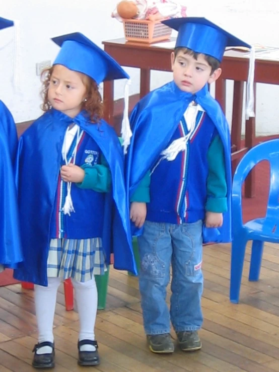 three children dressed up in blue and wearing graduation caps