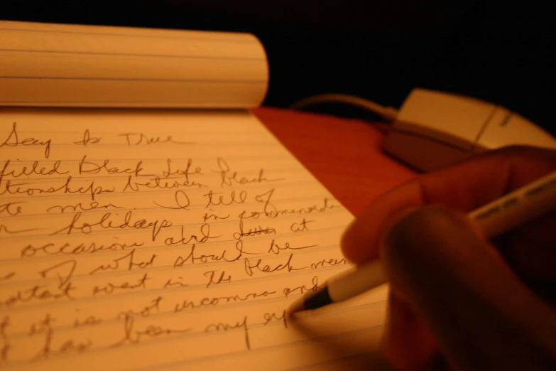 a person writing on paper with pen and paper notebook