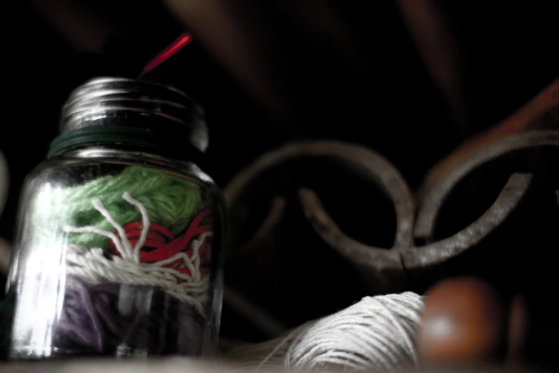 a close up of a glass jar with a knitting hook