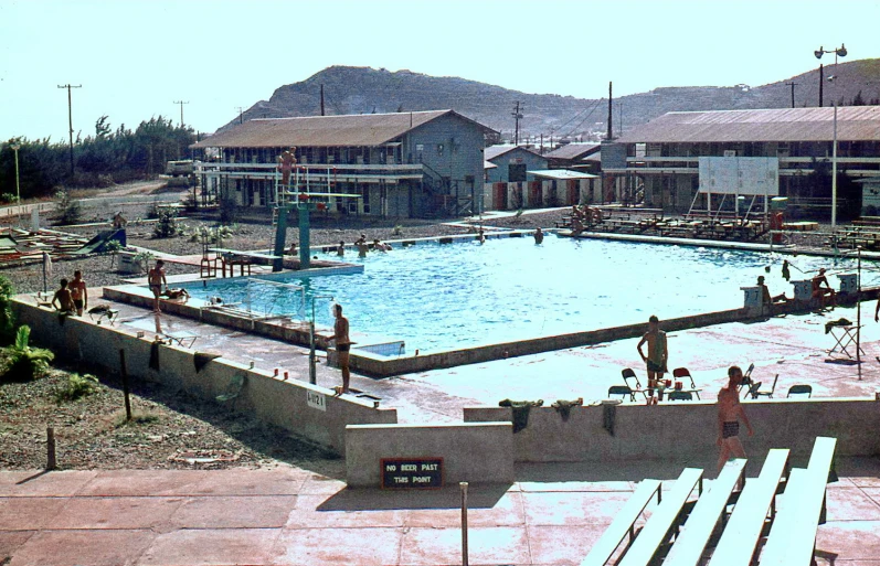 a large swimming pool and several children playing on the pool side