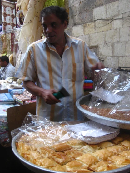 an older man standing over food items with plastic wrap on them