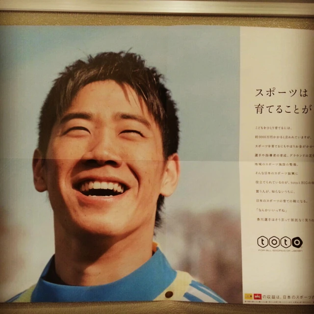 the face of an asian man smiling and holding soing