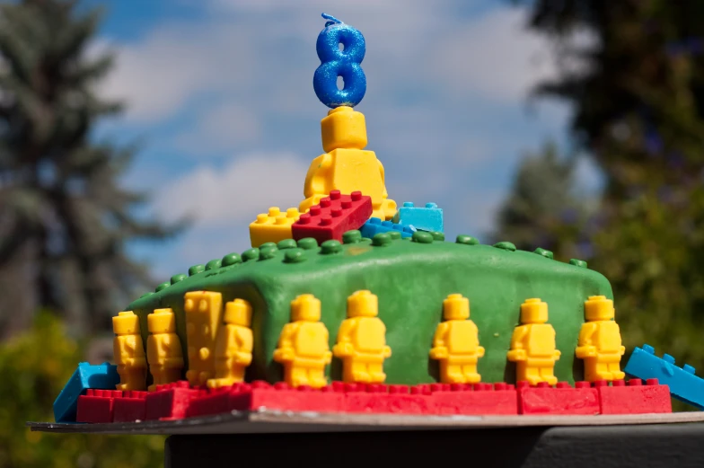 a lego cake with candles, figures and a tent