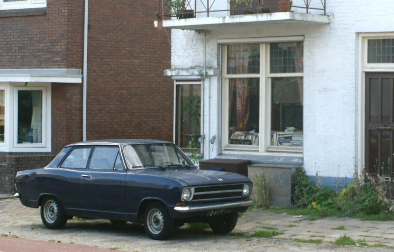 a small old fashioned car is parked in front of a house