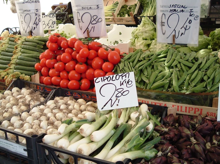 an open market with vegetables and signs for sale