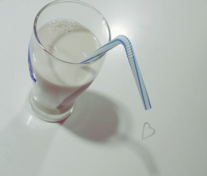 two straws in a glass of milk on a white table