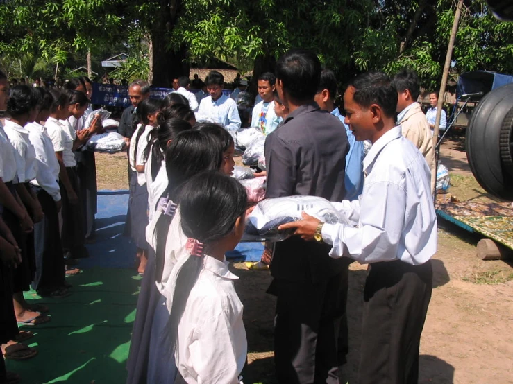 a  is handing soing to someone in front of a group