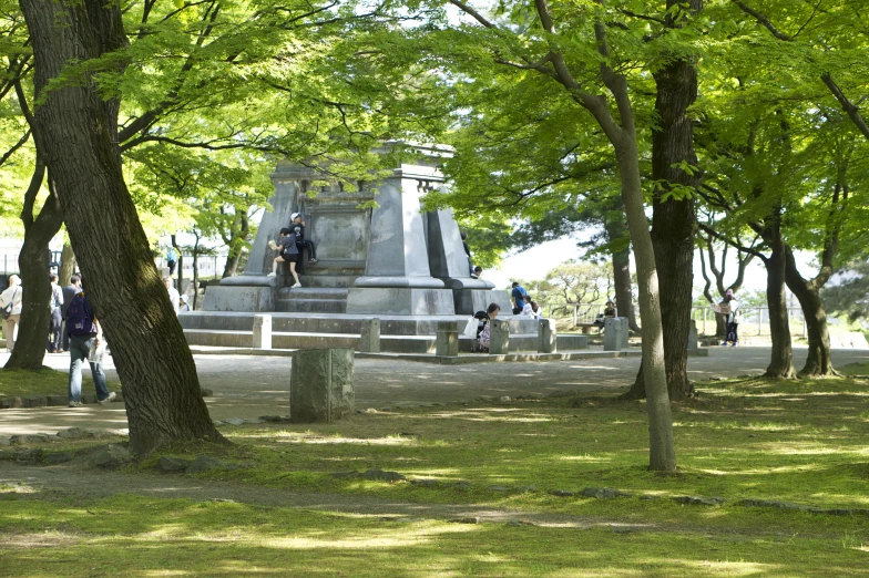 some people and a statue surrounded by trees