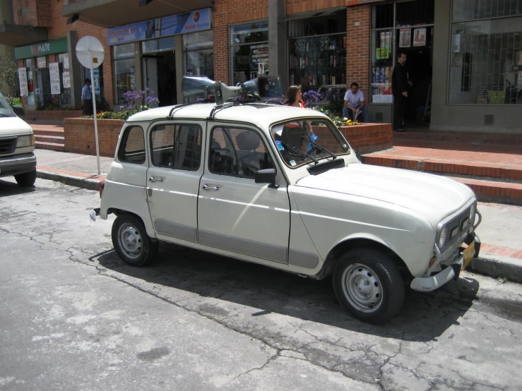 an old white vehicle parked in front of storefronts