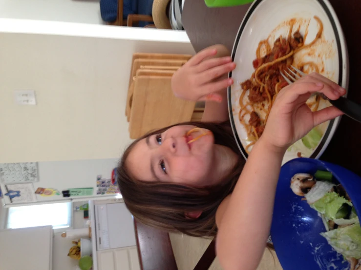 a little girl sitting at a table with a plate