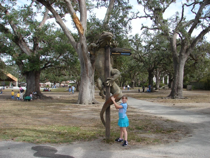 a little girl taking pictures of a sculpture of a dinosaur