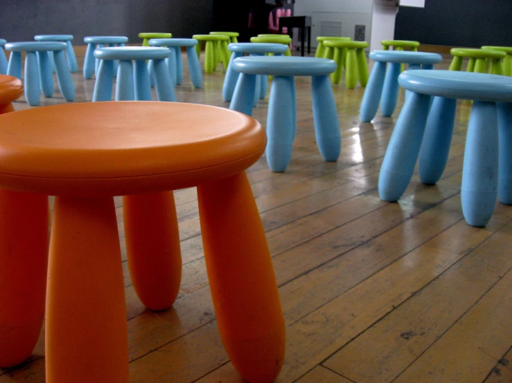 various colored plastic stools are sitting in an empty space