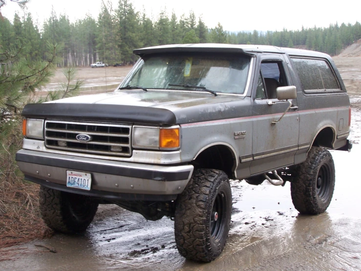 the large gray suv is driving in a field