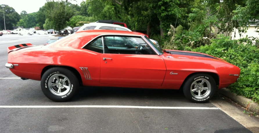 a red car parked in a parking space next to a shrub