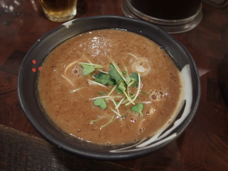 a bowl of soup and some vegetables sit on the table