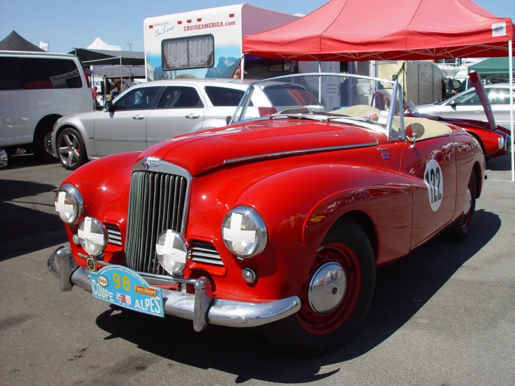 an old vintage convertible parked under a red tent