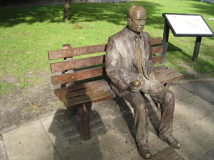 a statue is sitting on the side of a wooden bench