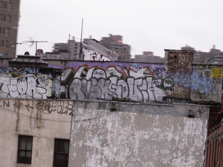 a wall covered in graffiti, with the city skyline in the background