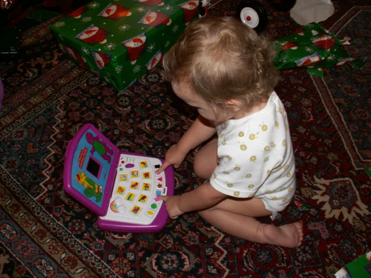 a baby playing with an open laptop sitting on the floor