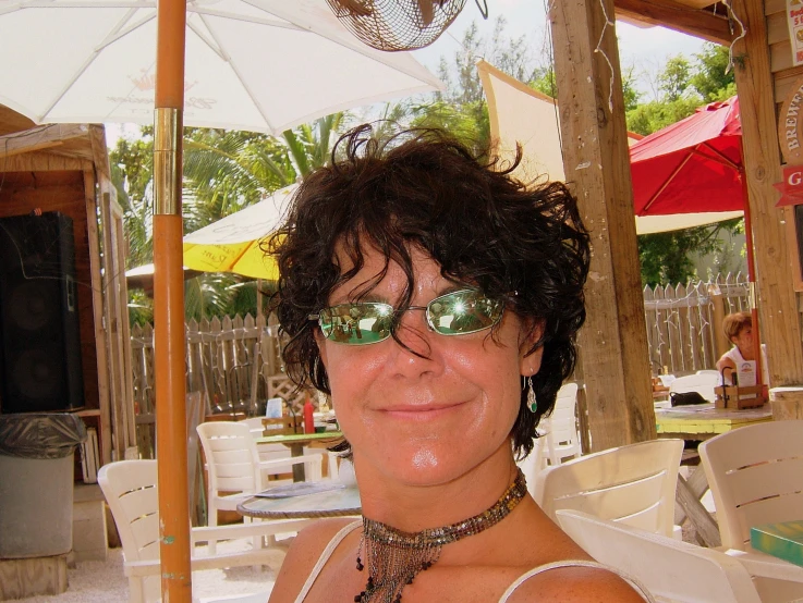 a woman in sunglasses sits under an umbrella